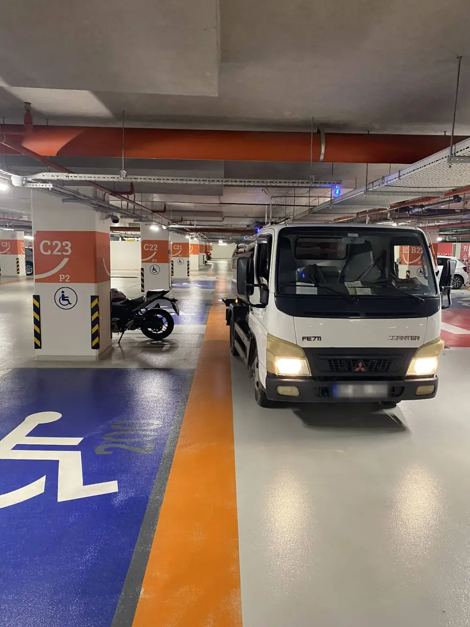Kapalı otoparkın içinde, park yerleri arasındaki yolda duran vidanjör aracı
