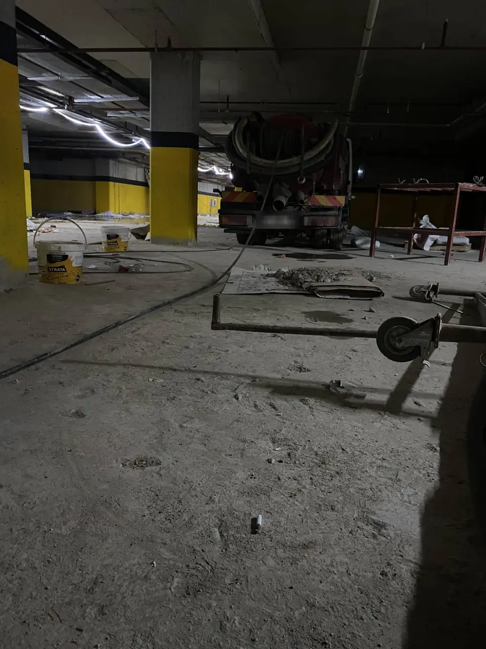 İnşaatı süren bir binanın bodrum otoparkında hortum makarasıyla mini vidanjör aracı